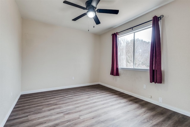 empty room featuring a ceiling fan, baseboards, and wood finished floors