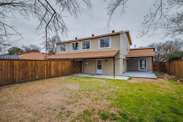 rear view of property with a yard, brick siding, a patio area, and a fenced backyard