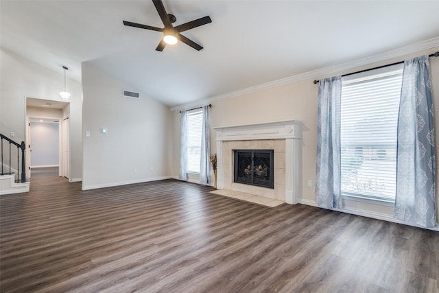 unfurnished living room with visible vents, a tile fireplace, ceiling fan, wood finished floors, and stairs