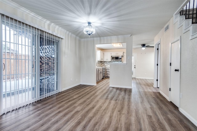 unfurnished living room featuring baseboards, ornamental molding, and wood finished floors