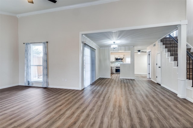 unfurnished living room featuring baseboards, ceiling fan, stairway, wood finished floors, and crown molding