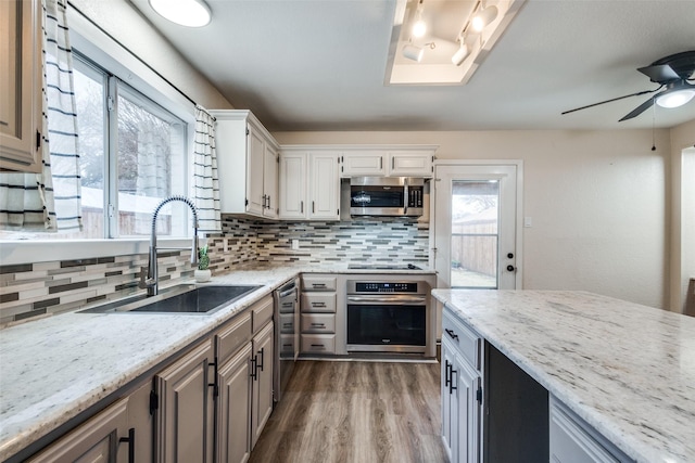 kitchen featuring dark wood-style flooring, stainless steel appliances, tasteful backsplash, white cabinetry, and a sink