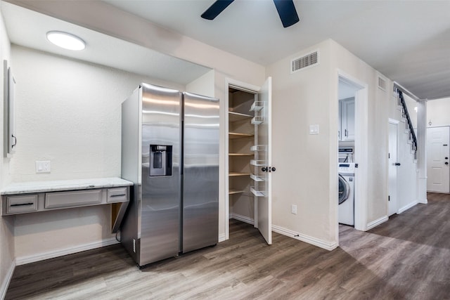 kitchen with washer / dryer, visible vents, wood finished floors, and stainless steel fridge with ice dispenser