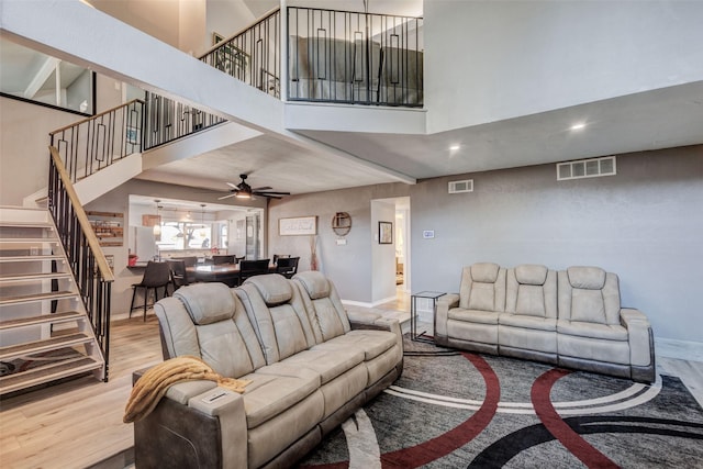 living area featuring baseboards, stairs, visible vents, and wood finished floors