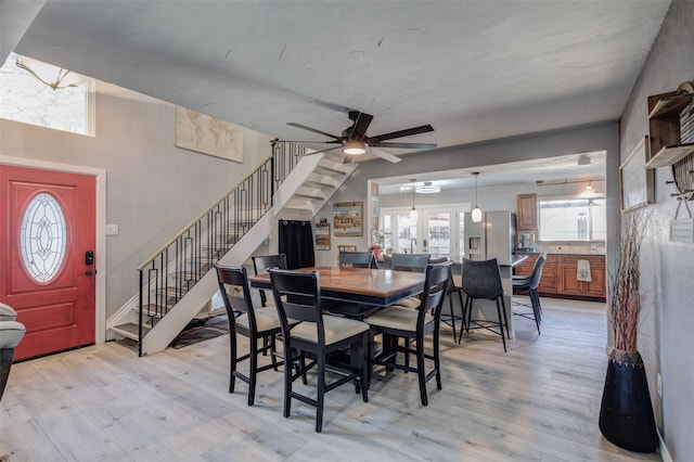 dining room with ceiling fan, stairway, and light wood-type flooring