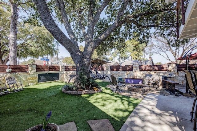 view of yard with a fenced backyard, a fire pit, and a patio