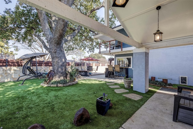 view of yard with a patio area, fence, and a balcony