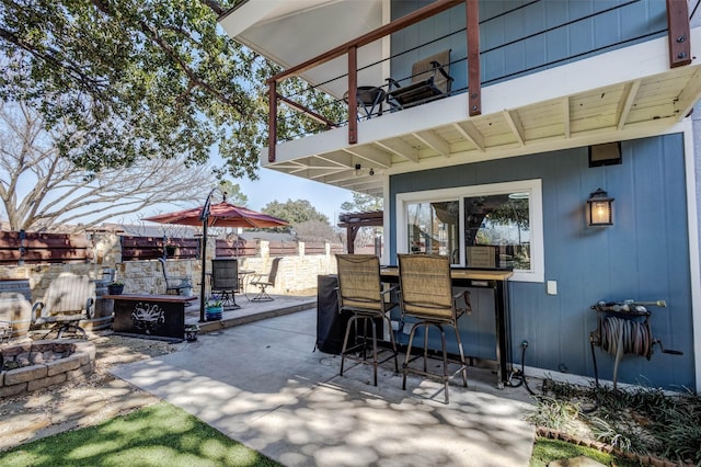 view of patio / terrace with an outdoor fire pit, fence, a balcony, and outdoor dining space