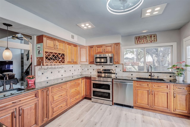 kitchen featuring decorative backsplash, dark stone counters, stainless steel appliances, and a sink