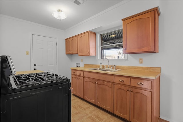 kitchen featuring black gas range, visible vents, ornamental molding, light countertops, and a sink