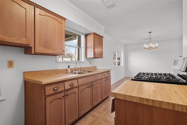 kitchen featuring butcher block countertops, a sink, visible vents, and a healthy amount of sunlight