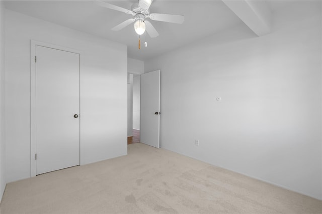 unfurnished bedroom featuring carpet, beam ceiling, and ceiling fan