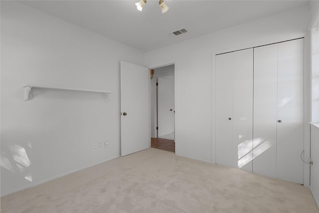 unfurnished bedroom featuring carpet floors, a closet, visible vents, and crown molding