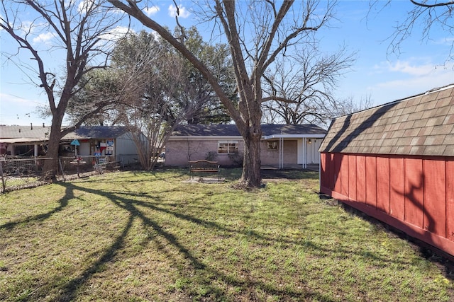 view of yard with a storage unit, fence, and an outbuilding