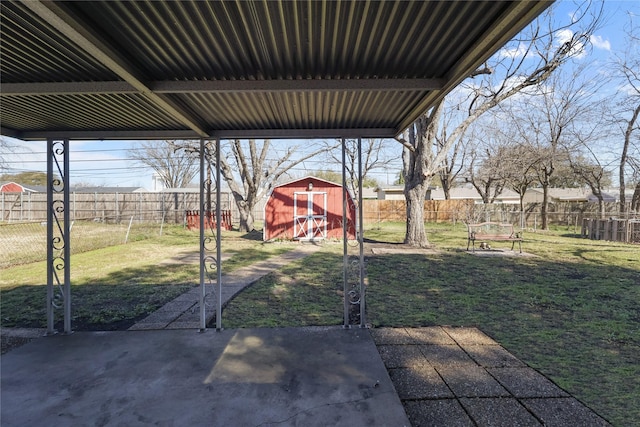 view of yard featuring a shed, an outdoor structure, a fenced backyard, and a patio