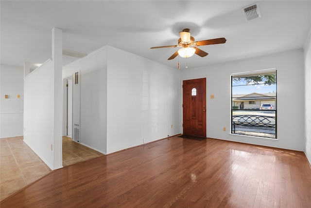 entrance foyer featuring a ceiling fan, visible vents, ornamental molding, and wood finished floors