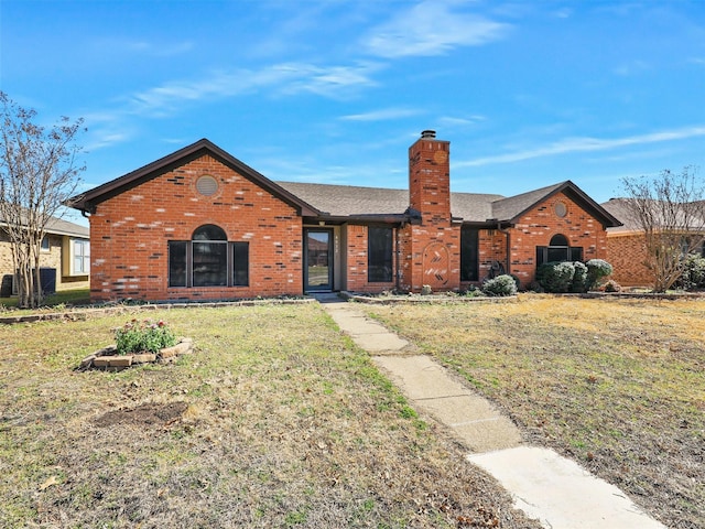 ranch-style house with roof with shingles, brick siding, a chimney, and a front yard