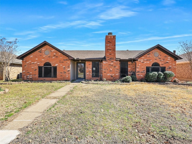 single story home featuring a front yard, roof with shingles, a chimney, and brick siding