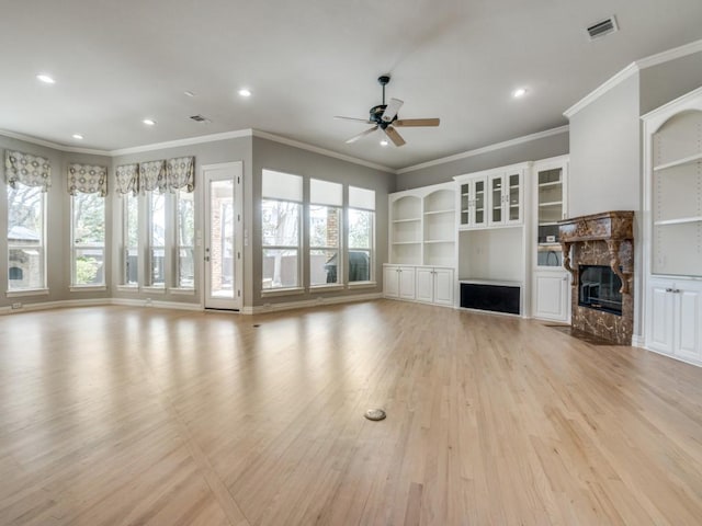 unfurnished living room with a ceiling fan, plenty of natural light, a fireplace, and light wood-style flooring