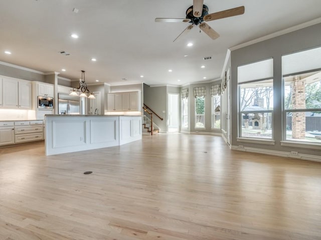 unfurnished living room with light wood-style flooring, ceiling fan with notable chandelier, visible vents, and recessed lighting