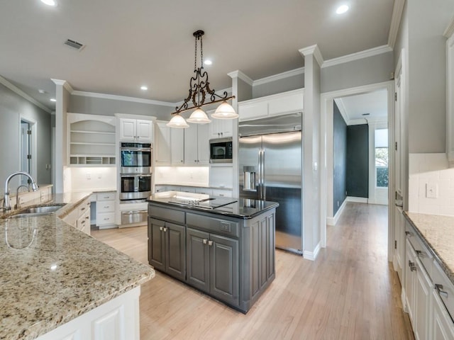 kitchen featuring built in appliances, a spacious island, a sink, white cabinets, and light wood finished floors