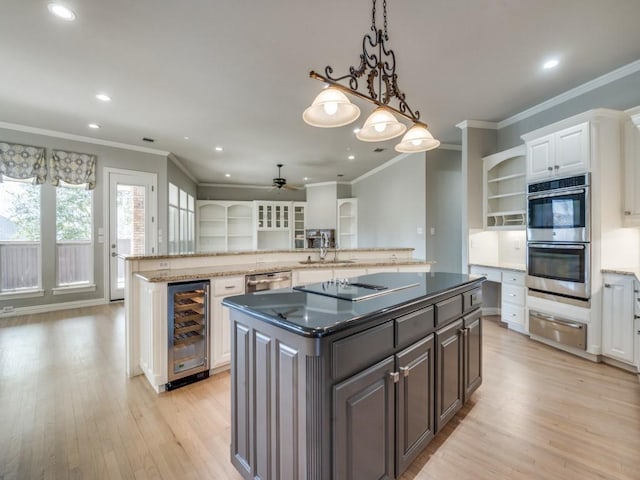 kitchen featuring wine cooler, a kitchen island, light wood-style floors, appliances with stainless steel finishes, and a warming drawer