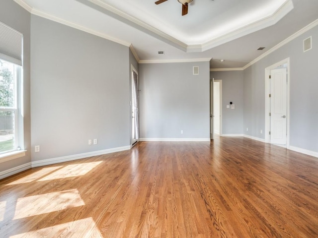 spare room with a raised ceiling, ceiling fan, baseboards, and wood finished floors