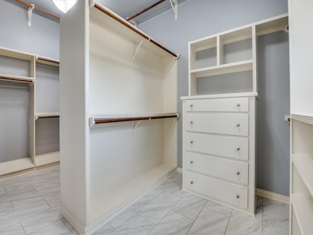 walk in closet featuring marble finish floor