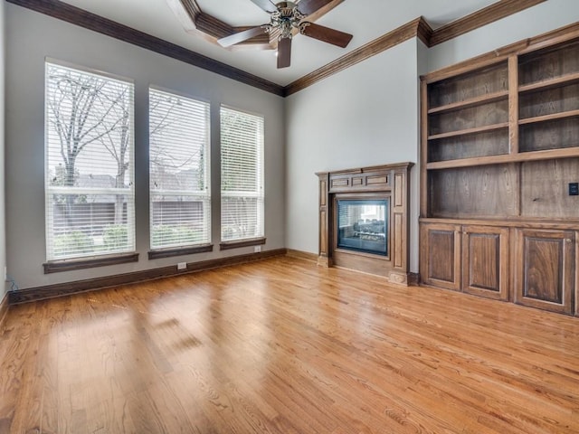 unfurnished living room featuring baseboards, ornamental molding, a glass covered fireplace, and light wood-style floors