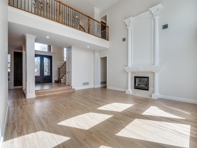 unfurnished living room featuring decorative columns, stairs, visible vents, and wood finished floors