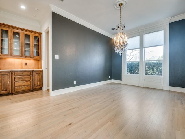 unfurnished dining area with light wood-type flooring, baseboards, and crown molding