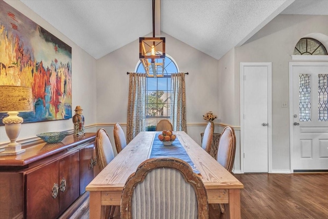 dining space featuring vaulted ceiling with beams, a textured ceiling, wood finished floors, and an inviting chandelier