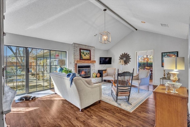 living area featuring visible vents, dark wood-type flooring, a textured ceiling, a brick fireplace, and beam ceiling