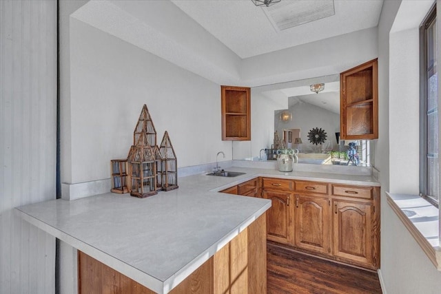 kitchen with light countertops, a sink, a peninsula, and open shelves