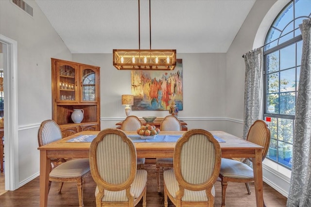 dining area with lofted ceiling, visible vents, and wood finished floors