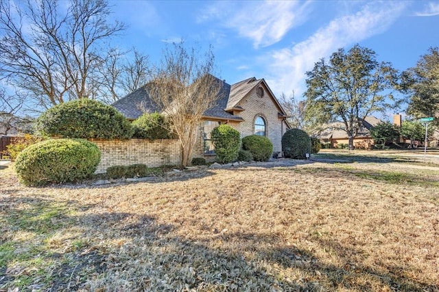 french country style house featuring roof with shingles and brick siding