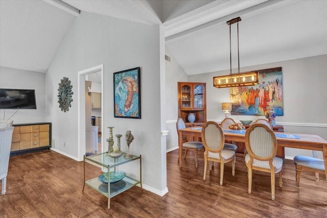 dining area featuring lofted ceiling with beams, baseboards, and wood finished floors