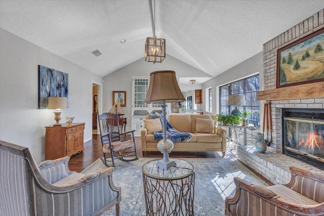 living room with lofted ceiling, a textured ceiling, a fireplace, wood finished floors, and visible vents