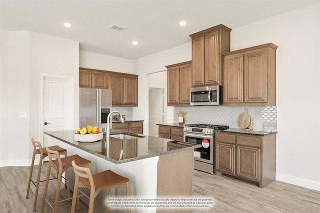 207 Cortese Ln, Alvarado, TX 76009 - kitchen with a sink, appliances with stainless steel finishes, light wood-style floors, brown cabinets, and a breakfast bar area