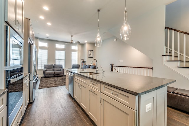 kitchen featuring dark wood-style floors, stainless steel appliances, open floor plan, a kitchen island with sink, and a sink