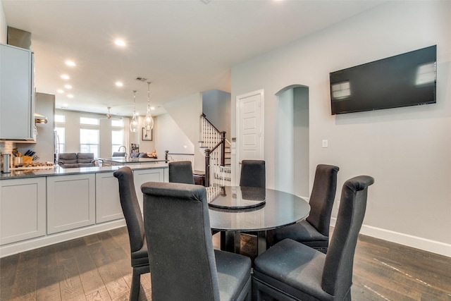 dining area featuring arched walkways, recessed lighting, baseboards, stairs, and dark wood finished floors