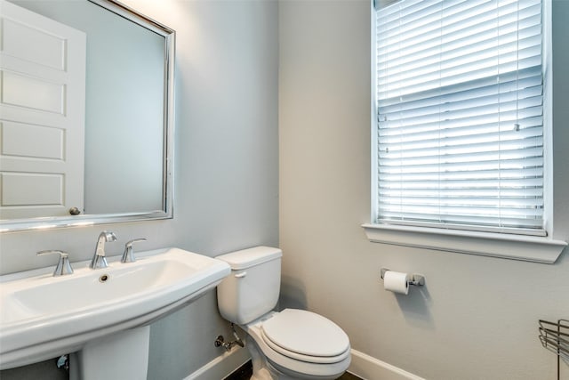 bathroom featuring baseboards, a sink, and toilet