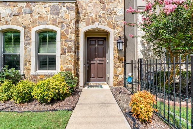 entrance to property with stone siding and fence