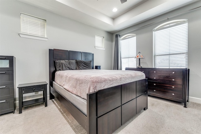 bedroom featuring a tray ceiling, light colored carpet, baseboards, and recessed lighting