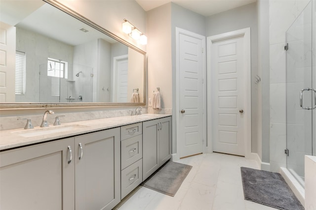 full bath with double vanity, marble finish floor, a shower stall, and a sink