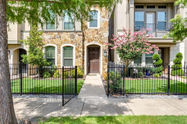 view of front of home featuring stone siding, a fenced front yard, and stucco siding