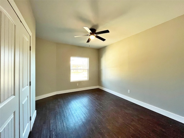 spare room with dark wood-style floors, ceiling fan, and baseboards