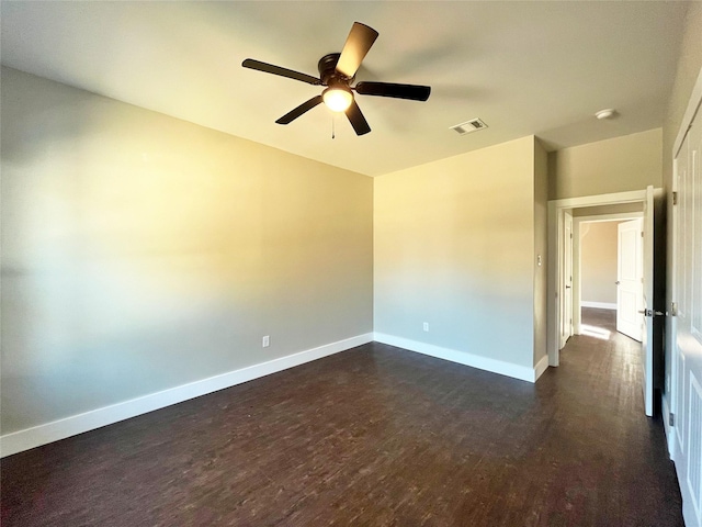 empty room with baseboards, visible vents, ceiling fan, and dark wood-style flooring