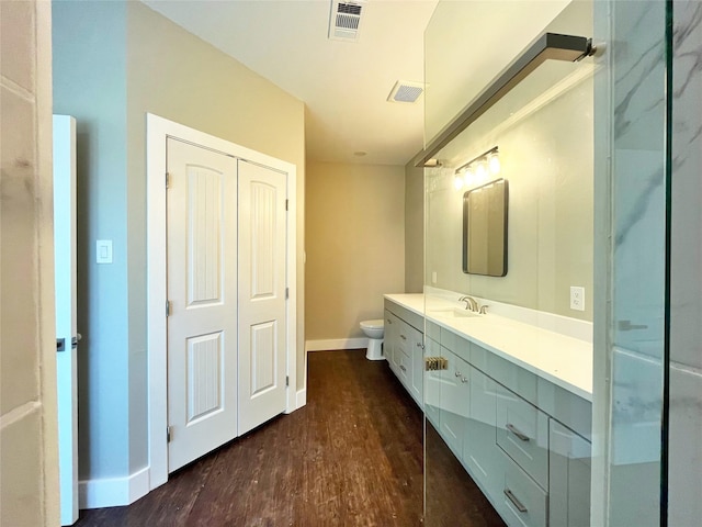 bathroom featuring toilet, wood finished floors, vanity, visible vents, and baseboards