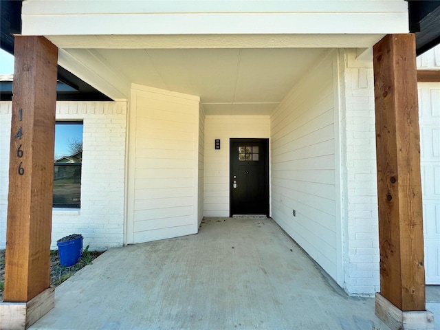 entrance to property featuring a garage and brick siding